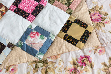 Part of color patchwork quilt with vintage flowers pattern as background. Colorful Scrappy blanket. Handmade. Hobby Concept.