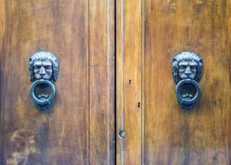 Lion head knockers on an old wooden door in Tuscany, Italy.