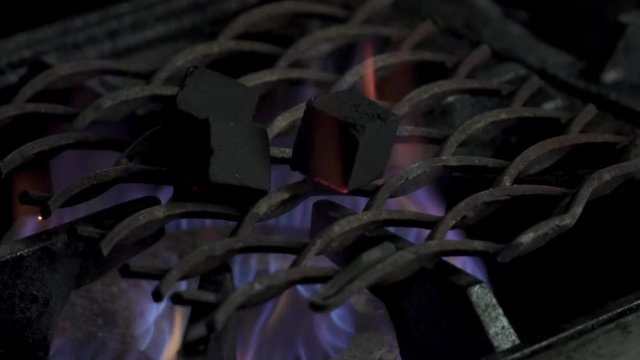 Burning coals for hookah in the kitchen closeup, slow motion