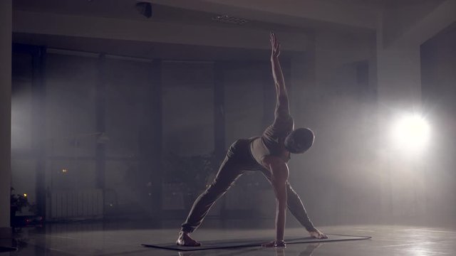 Male yoga practician performs the stand on arms in the gym.