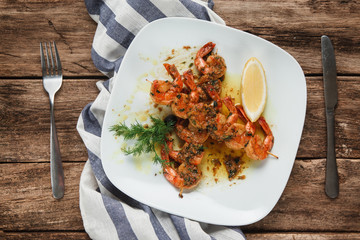 Served table with appetizing japanese food. Tasty fried shrimps with spices, herbs and lemon, flat lay on wooden background.