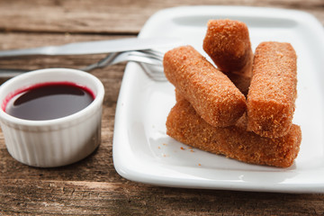 Appetizing fresh nuggets are served on white plate with red chili sauce, close up view. Restaurant menu photo.
