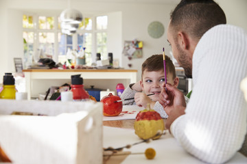 Father And Son Decorating Halloween Pumpkins At Home