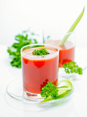 tomato juice in transparent glasses with parsley and cucumber, close up