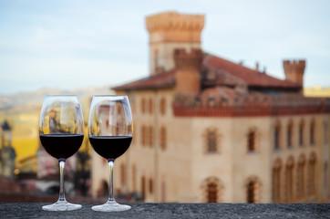 Two glasses of Barolo wine on a windowsill with the castle of Barolo (Piedmont, Italy) blurred on the background - 141346256