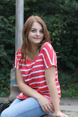 beautiful woman in a red shirt sitting on the railing. stay after the walk