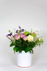 Bouquet of flowers in a white vase against a white background.