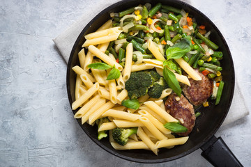 Pasta penne with green vegetables and meat cutlets.