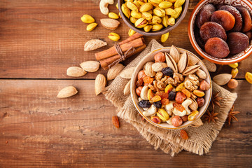 Mix of nuts and dried fruits on a old rustic table. Gold pistachios, cashews, hazelnuts, almonds. Food background with copyspace