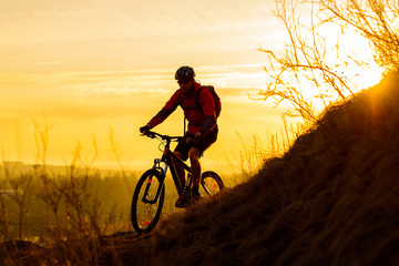 Fototapeta na wymiar Silhouette of Enduro Cyclist Riding the Mountain Bike on the Rocky Trail at Sunset. Active Lifestyle Concept. Space for Text.