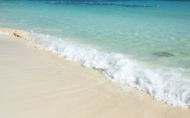 Fototapeta na wymiar The Caribbean sea and the beautiful beach. Small waves hitting the shore on a sunny day.
