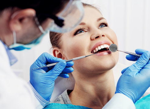 Female patient in dental clinic treating or examining teeth. Health care concept. 