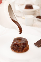 Chocolate flowing down from sauceboat. French dessert cake mi-cuit