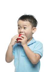 Asian baby boy holding and eating red apple, isolated on white