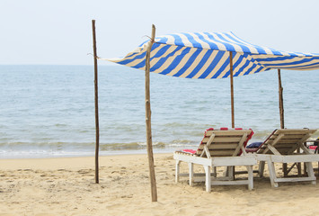 Two chaise lounges under a canopy on the beach near the ocean