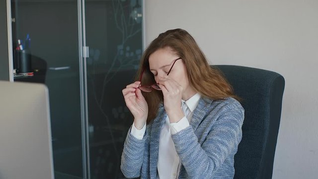 Business woman putting on her glasses and reading a note while working. Slow motion