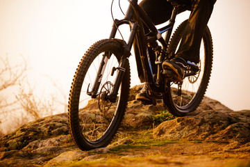 Enduro Cyclist Riding the Bike Down Rocky Hill at Sunset. Close up Extreme Sport Concept. Space for Text.
