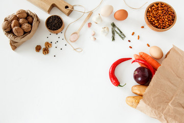 Vegetables, nuts, beans, potatoes, red peppers, chicken eggs, other food and kitchen appliances lie on a white background. Space for text, daylight, horizontal image.