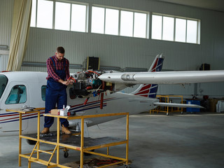 Young man repairing airplane in hangar