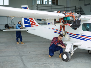 Young man and woman repairing jetliner