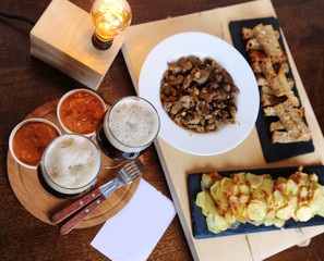 Beer and snacks. Lamp of Edison. Hipster still life. A wooden board. Potato chips, fries. Garlic toast. Plugs with wooden handles