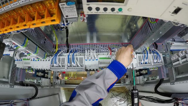 Technician installing electrical equipment into fuse switch box and screw it with screwdriver. 4K.
