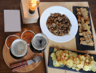 Beer and snacks. Lamp of Edison. Hipster still life. A wooden board. Potato chips, fries. Garlic toast. Plugs with wooden handles