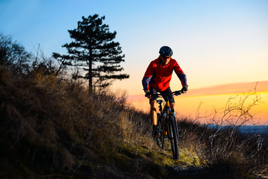 Enduro Cyclist Riding the Mountain Bike on the Rocky Trail at Sunset. Active Lifestyle Concept. Space for Text.
