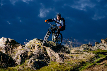 Fototapeta na wymiar Enduro Cyclist Riding the Bike on the Rock at Night. Extreme Sport Concept. Space for Text.