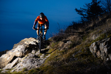 Fototapeta premium Enduro Cyclist Riding the Bike on the Rock at Night. Extreme Sport Concept. Space for Text.