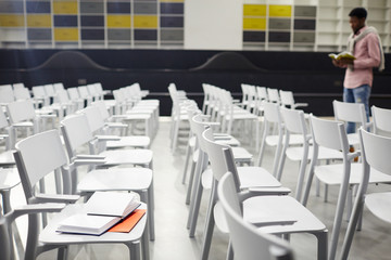Rows of white plastic chairs and student preparing for exama on background