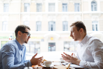 Young analysts having conversation by business lunch in cafe