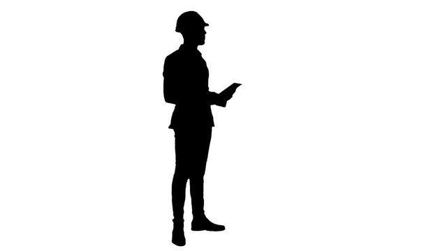 Silhouette Engineer in helmet carrying out inspection using tablet
