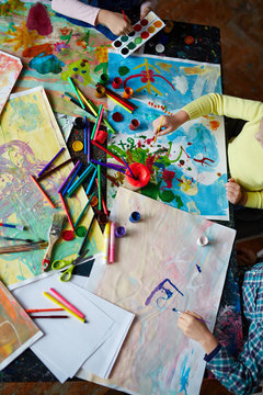 Hands of kids with paintbrushes painting big picture