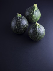Round courgettes isolated on dark background