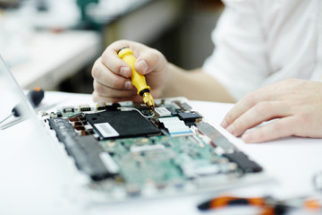 Closeup shot of unrecognizable man assembling circuit board in laptop using screwdriver and...