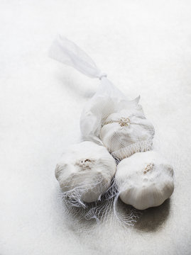 Studio shot, overhead view of garlic bulbs in white netting