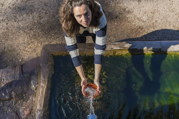 Chica en una fuente de agua natural.
