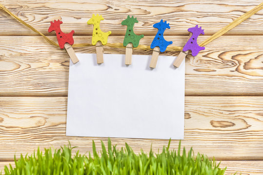 clothespin hanging with blank paper on wooden background