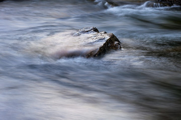 Stone in a river with fast moving water around