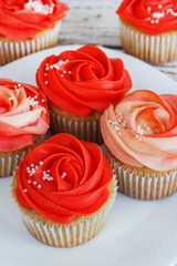 Vanilla cupcakes decorated with a red rose from a cream on a white background