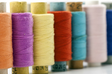 Reels or spools of multicolored sewing threads. Threads of all colors. Shallow depth of field. Close-up macro shot.