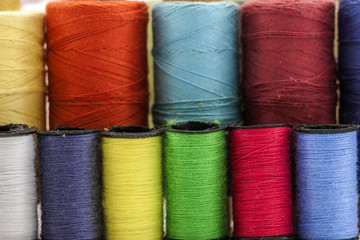 Reels or spools of multicolored sewing threads. Threads of all colors. Shallow depth of field. Close-up macro shot.