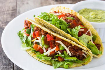 Traditional Mexican tacos with meat and vegetables on wooden background
