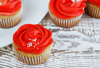 Vanilla cupcakes decorated with a red rose from a cream on a white background