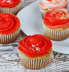 Vanilla cupcakes decorated with a red rose from a cream on a white background