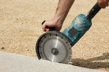 Worker hands holding angle grinder with diamond cutting disc for concrete