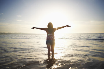 Rear view of woman standing in sea with arms open, Cascais, Portugal