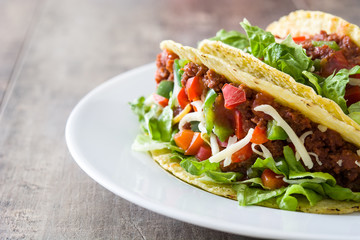 Traditional Mexican tacos with meat and vegetables on wooden background
