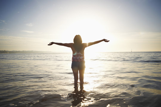 Rear view of woman standing in sea with arms open, Cascais, Portugal